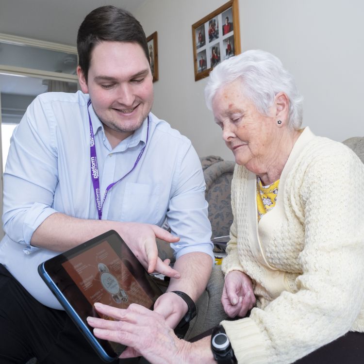 Men in blue shirt showing a lady in yellow how to use a tablet