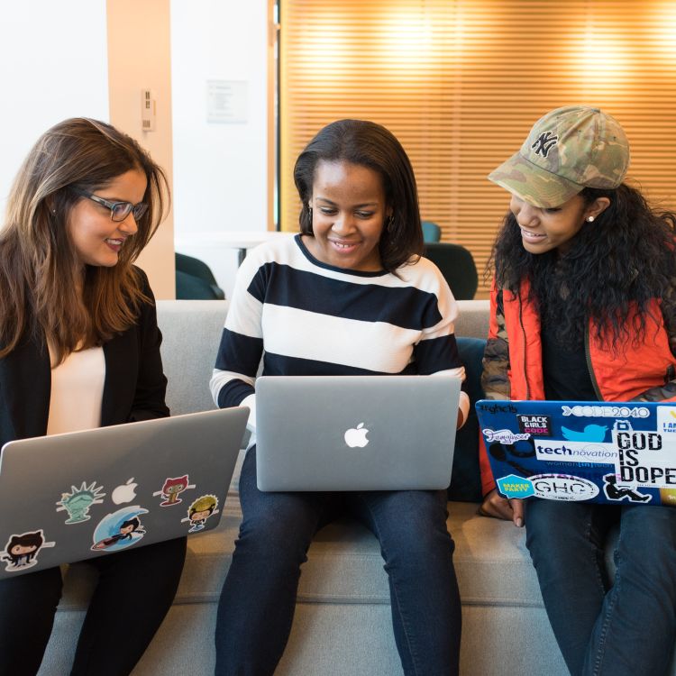 Three ladies interacting and working on their laps