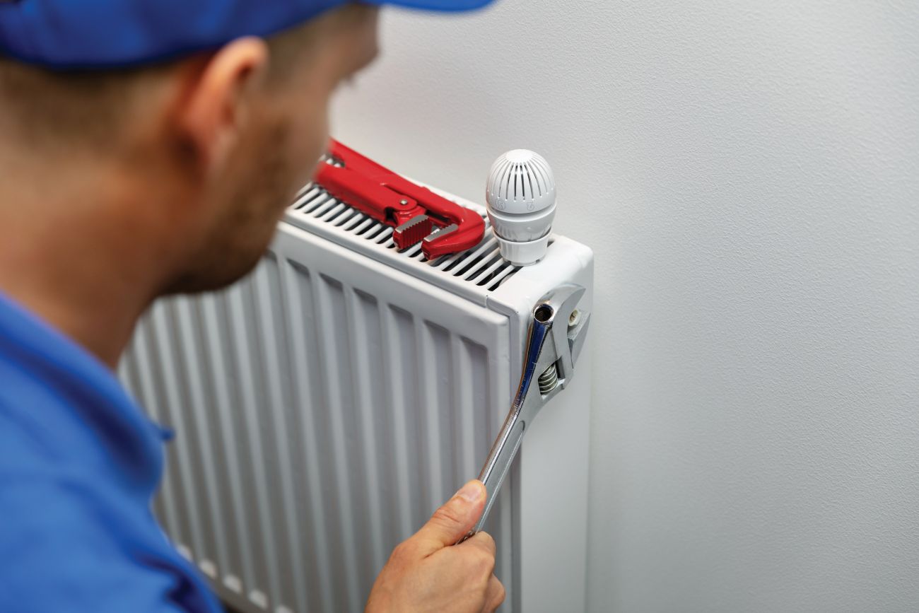 Man fixing a radiator with a spanner