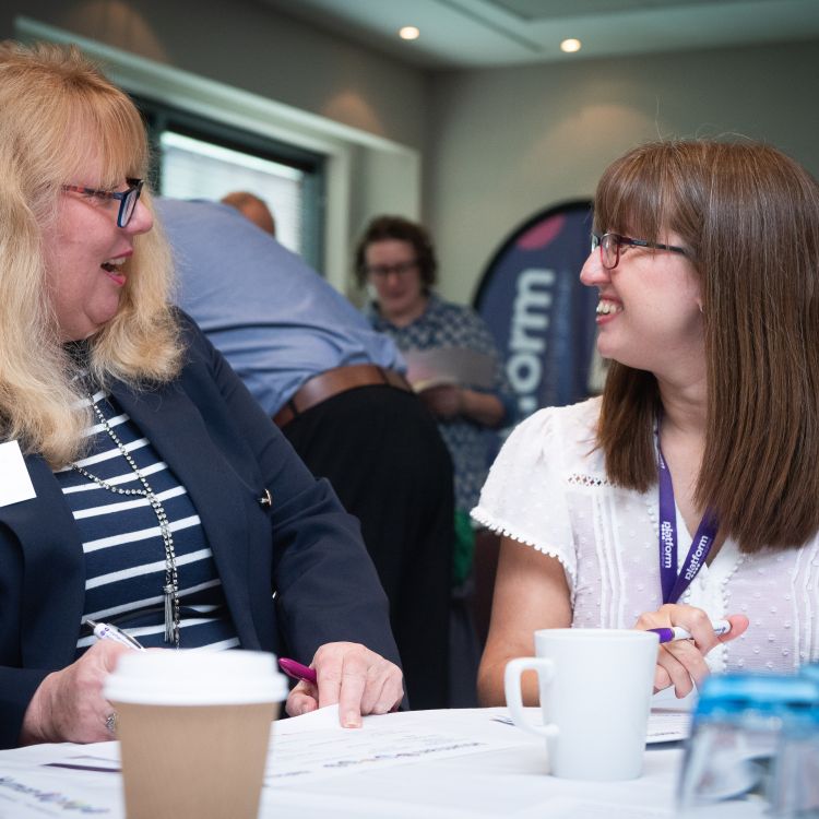 Two ladies talking to each other and smiling