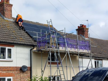 Solar PV panels being fitted on house with scaffolding in place